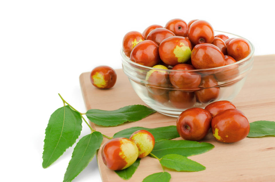 Ripe jojoba fruits in a bowl on a wooden tabletop. Chinese date fruit