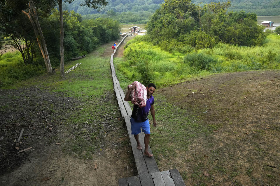 Fisherman Marco Aurelio Cauto Viana, carries pieces of a pirarucu fish in San Raimundo settlement, at Medio Jurua region, Amazonia State, Brazil, Monday, Sept. 5, 2022. Indigenous communities working together with non-Indigenous riverine settlers manage the pirarucu in preserved areas of the Amazon. Most of it is exported, and the U.S. is the primary market. (AP Photo/Jorge Saenz)