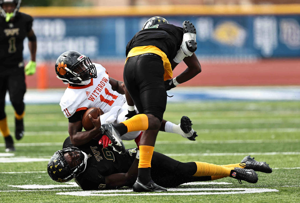 Withrow quarterback Troy Montgomery (11) is tackled by Taft defenders Elias Rudolph (9) and Tayshawn Banks in a football game between Taft and Withrow high schools Saturday, Sept. 24, 2022.