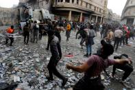 Iraqi demonstrators throw stones towards Iraqi security forces during the ongoing anti-government protests in Baghdad