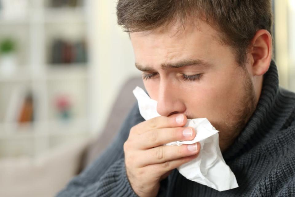 Man coughing covering mouth with a tissue