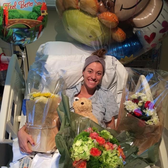 Brittany Williams surrounded by balloons and flowers in hospital bed