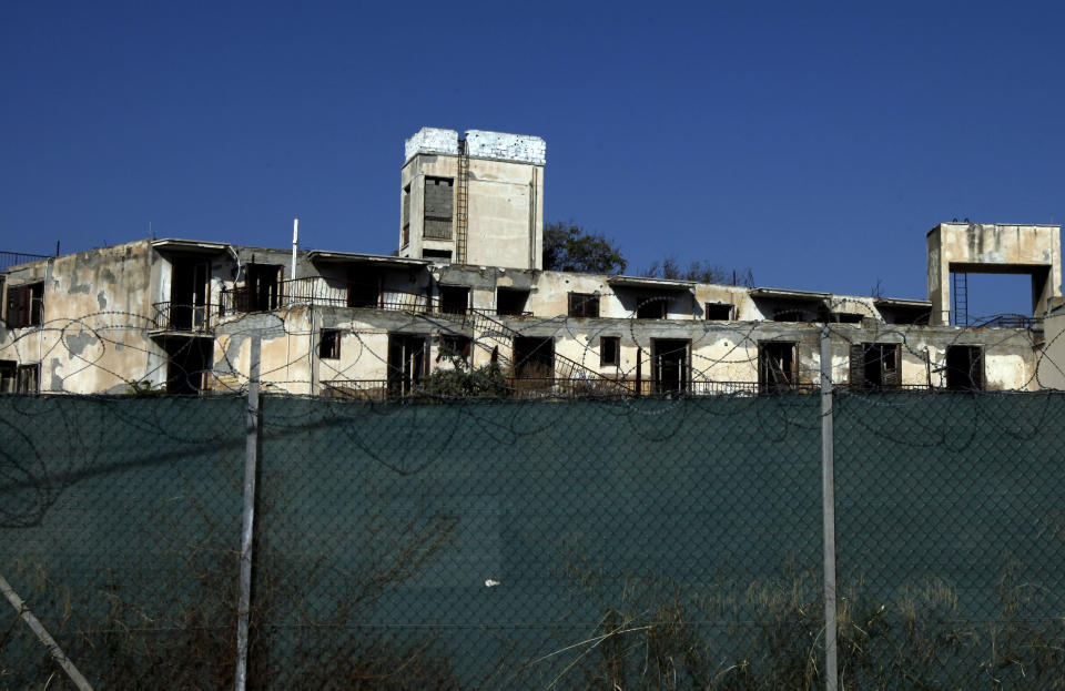 In this photo taken on Wednesday Nov. 6, 2019, an abandoned building inside the U.N buffer zone is seen behind a fence that divides the Greek Cypriot south and the Turkish Cypriot north, in divided capital Nicosia, Cyprus. As the world commemorates 30 years since the fall of the Berlin Wall, the bullet-riddled sandstone walls of abandoned, crumbling homes and concrete machine gun nests dotting in Cyprus' no-man's land are a reminder of Europe's last divided country. (AP Photo/Petros Karadjias)