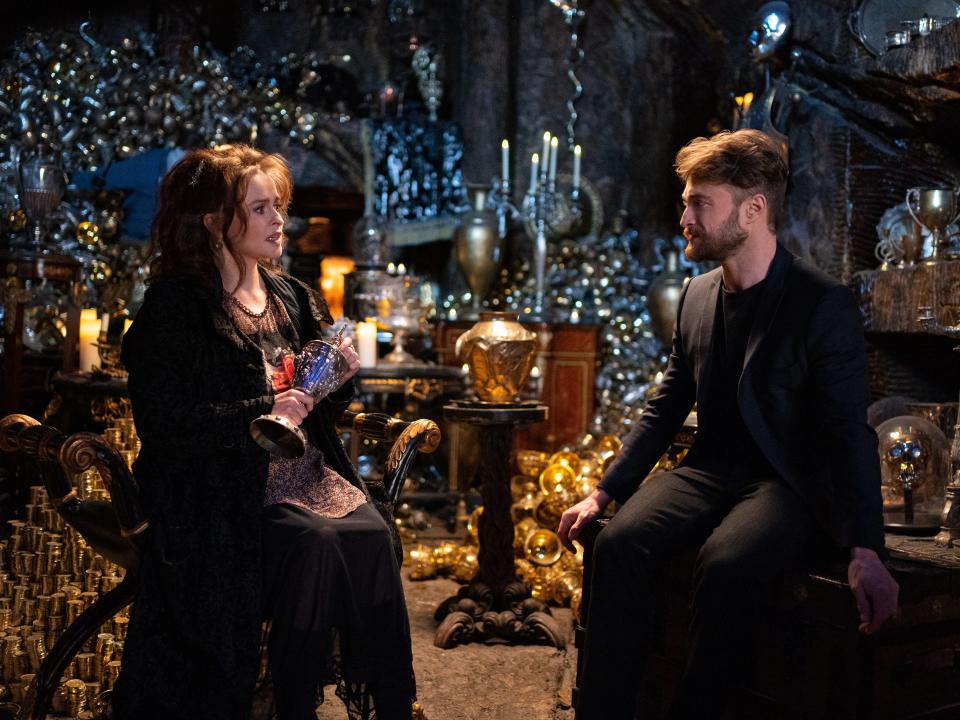 helena bonham carter and daniel radcliffe sitting together in 2021, looking at each other in a recreation of the lestrange vault in gringotts bank in the harry potter 20th anniversary reunion special