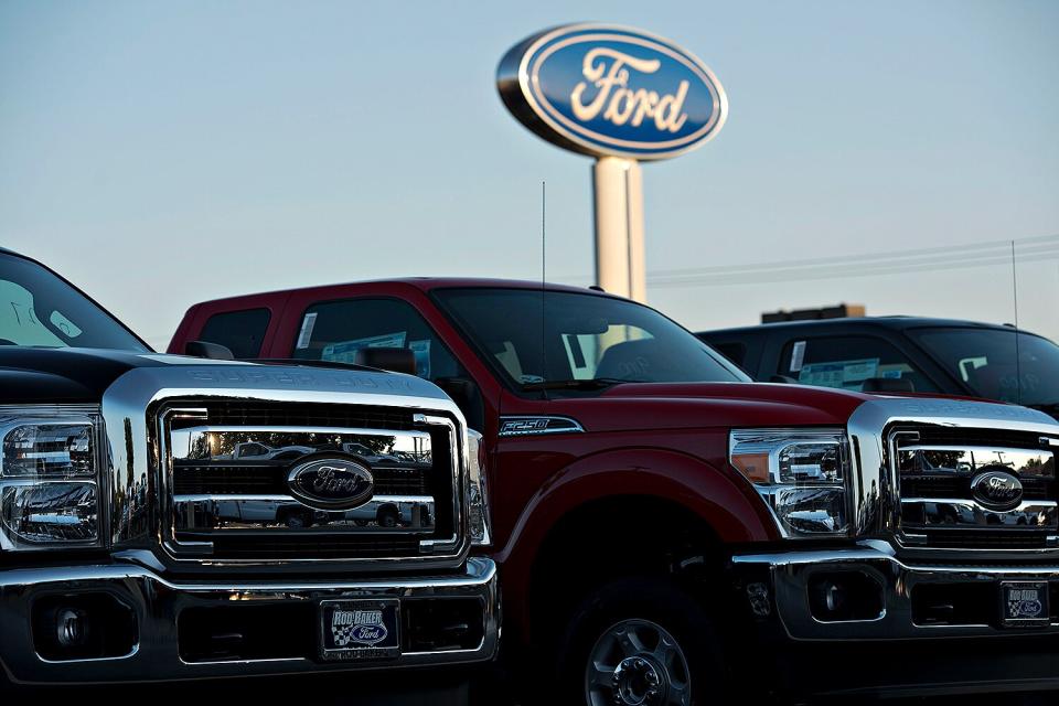 A Ford Motor Co. logo stands behind a row of F-250 pickup trucks at the Rob Baker Ford dealership in Plainfield, Illinois, U.S., on Wednesday, July 23, 2014.