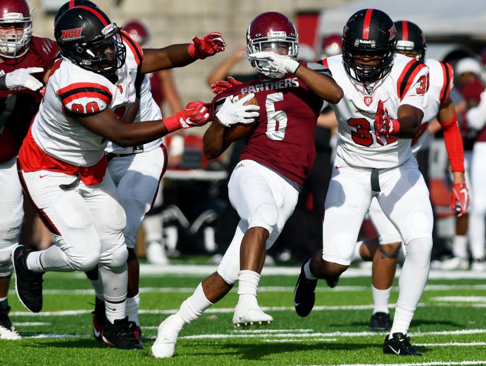 Antwuan Haynes of Florida Tech tries to fight through the tackle of Zeke Stringer (90) and Kendall Brooks (30) of North Greenville during Saturday's game. 
