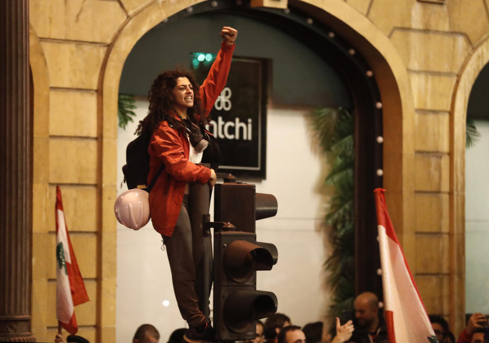 An anti-government protesters stands on a traffic light, as she shouts slogans during a protest near the parliament square, in downtown Beirut, Lebanon, Sunday, Dec. 15, 2019. Lebanese security forces fired tear gas, rubber bullets and water cannons Sunday to disperse hundreds of protesters for a second straight day, ending what started as a peaceful rally in defiance of the toughest crackdown on anti-government demonstrations in two months. (AP Photo/Hussein Malla)