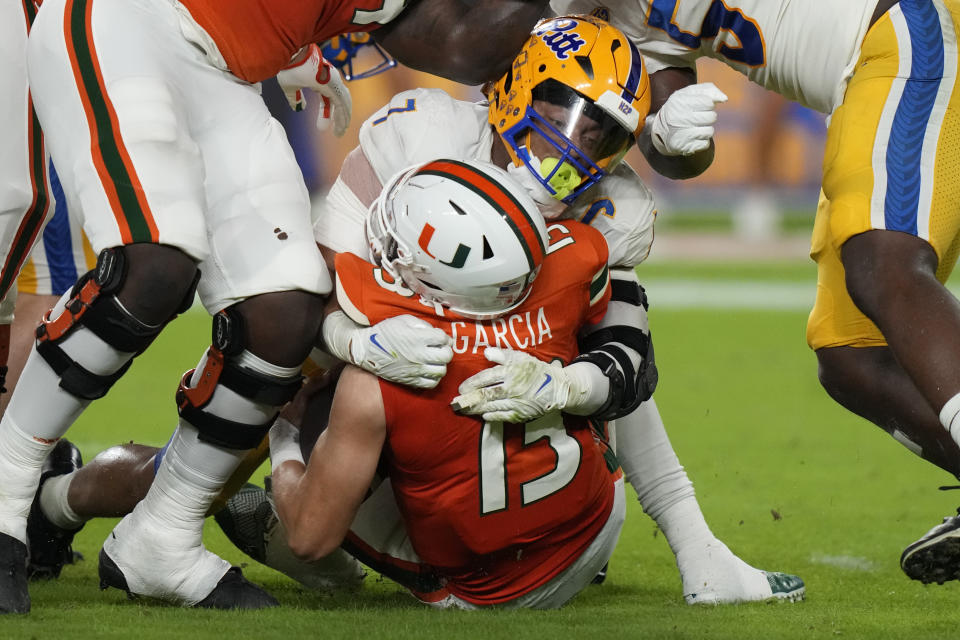 Miami quarterback Jake Garcia (13) is tackled by Pittsburgh linebacker SirVocea Dennis (7) during the first half of an NCAA college football game, Saturday, Nov. 26, 2022, in Miami Gardens, Fla. (AP Photo/Lynne Sladky)