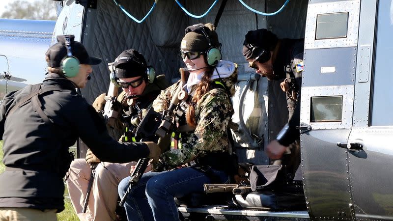 A HeliBacon employee checks the firearm of 25-year-old hunter Regan Fehrenbacher of Houston, Texas, before a feral hog-hunting trip via helicopter in Bryan