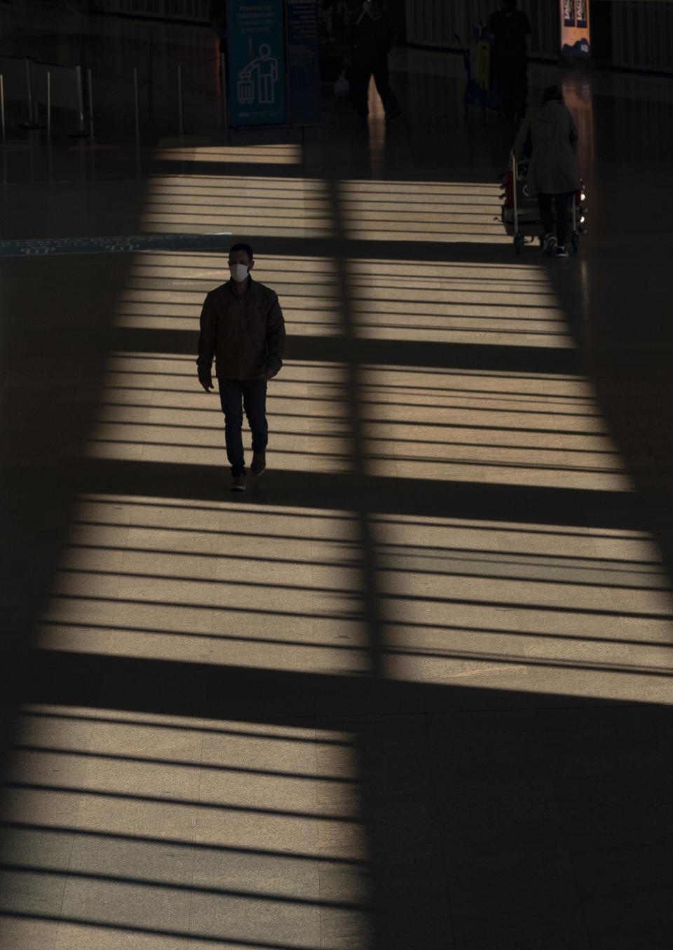 A man walks through an almost empty corridor inside the Sao Paulo International Airport in Guarulhos, Brazil, Wednesday, May 27, 2020. According to the airport administration, Brazil's busiest airport has had an average reduction of 85% in flights, due to the COVID-19 pandemic. (AP Photo/Andre Penner)