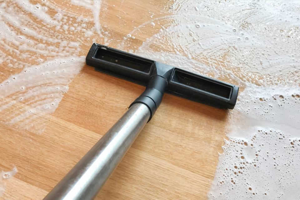 Woman mopping/vacuuming hardwood floors to prevent mold