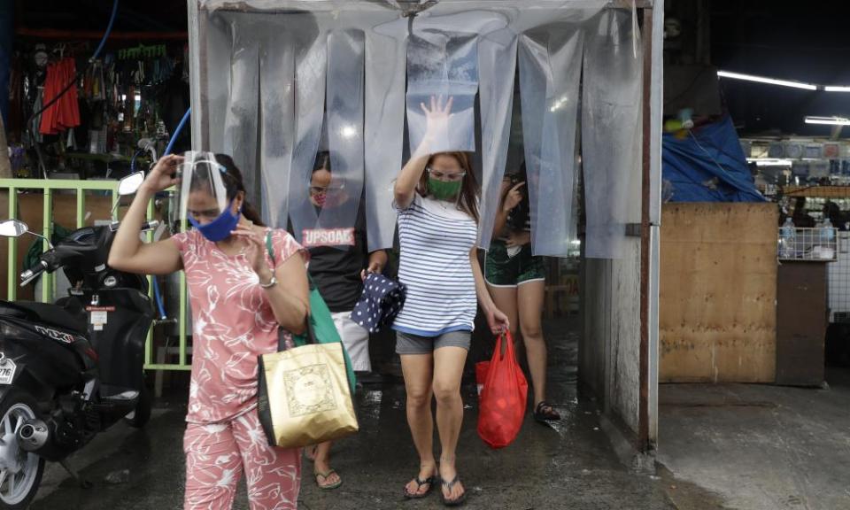 Women exit from a disinfecting area after buying food at a public market in preparation for stricter lockdown measures in Quezon city