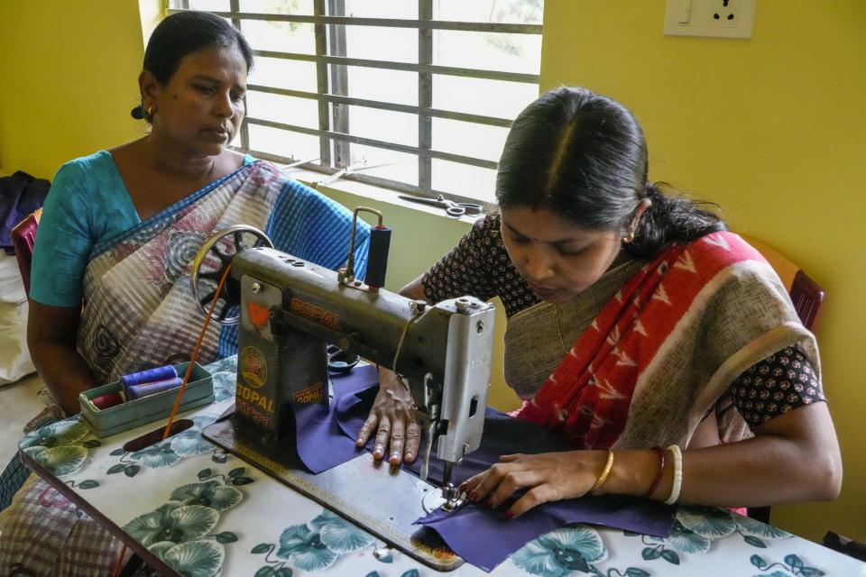 Kakali Halder, left, inspects sewing work in Mathurapur, South 24 Parganas, India, Monday, March 27, 2023. Halder and several hundred fellow seamstresses at Mathurapur Sanghati Swayamber Sangha, a group that make clothing items and share the proceeds between them, have worked with the stress of trying to get orders out when they can't rely on the electricity. (AP Photo/Bikas Das)