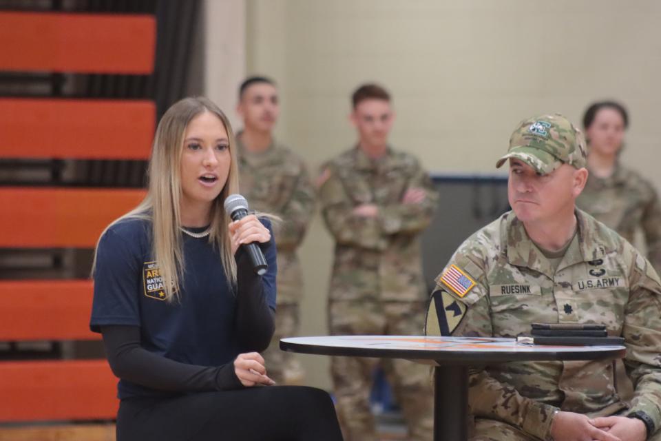 Riley Ammenhauser, a University of Michigan women's track and field team member, answers a question during an assembly Friday at Tecumseh High School with the Michigan Army National Guard and U-M student-athletes. Listening is Army Lt. Col. Eli Ruesink of Adrian.