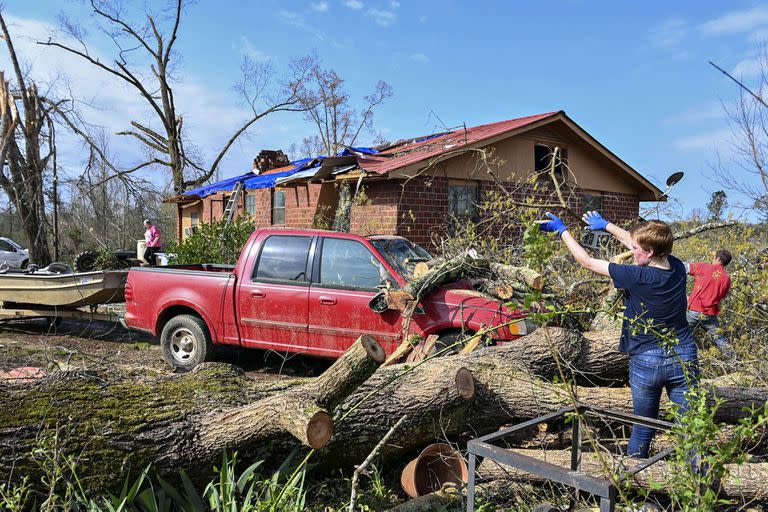 Emily Magourik ayuda a remover árboles caídos del hogar de sus abuelos, luego del paso del tornado, en Ohatchee, Alabama