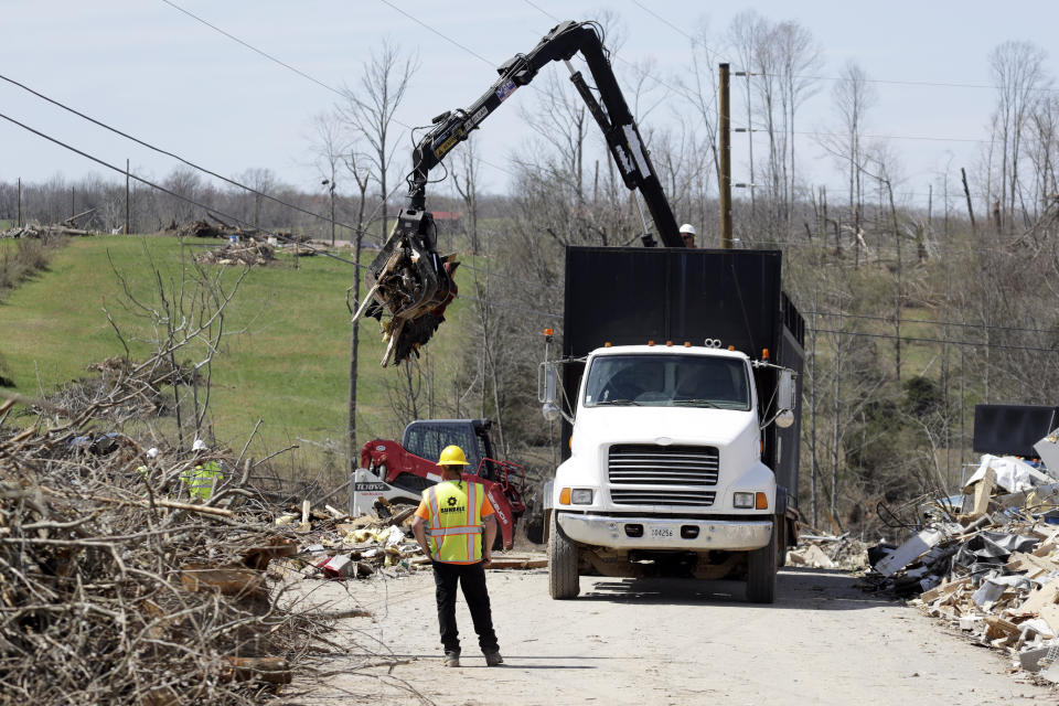 In this March 26, 2020, photo, workers clear tornado debris from yards in Cookeville, Tenn. People still reeling from the deadly twisters that hit the state on March 3 now have to confront life in the age of coronavirus. (AP Photo/Mark Humphrey)