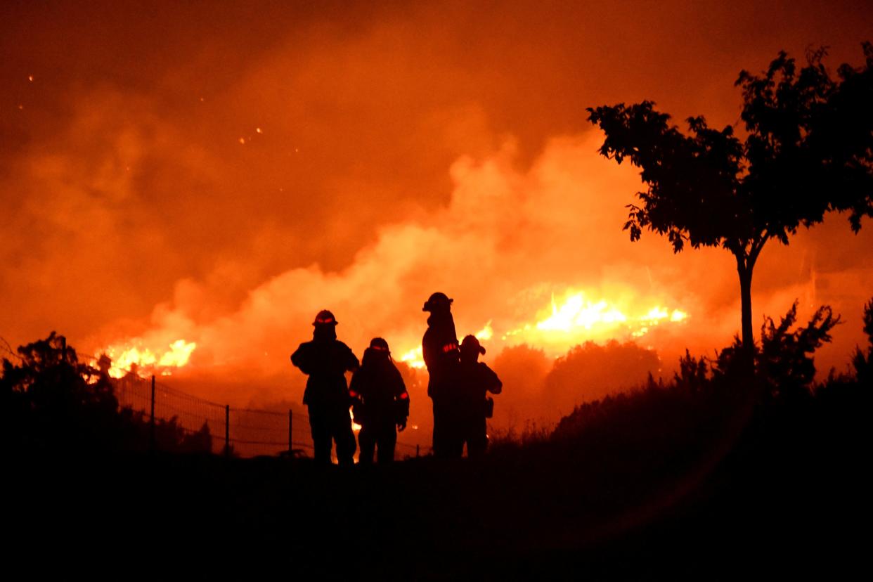 Los Angeles County firefighters keep watch on the Bobcat Fire as it burns through the night in Juniper Hills, California on 19 September 2020 (Reuters)