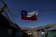 A Chilean flag hangs inside a camp where migrants from Haiti, Peru and Colombia, set up a homes and call "Dignidad," or Dignity, in Santiago, Chile, Thursday, Sept. 30, 2021. There are 180,000 Haitians in Chile, of whom “almost 70,000 reside in the country permanently,” said deputy interior minister Juan Francisco Galli. (AP Photo/Esteban Felix)