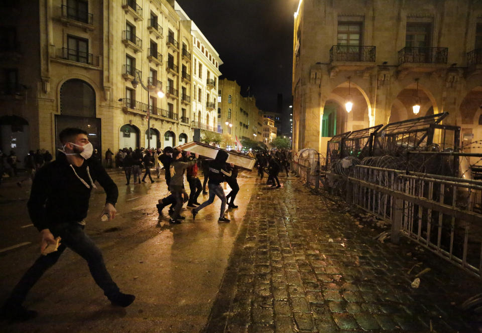 Anti-government protesters throw stones against the riot police, during ongoing protests against the political elites who have ruled the country for decades, in Beirut, Lebanon, Sunday, Jan. 19, 2020. Lebanese security forces used tear gas, water cannons and rubber bullets in clashes with hundreds of anti-government protesters outside the country's Parliament on Sunday, as violence continued to escalate in a week of rioting in the capital. (AP Photo/Hassan Ammar)