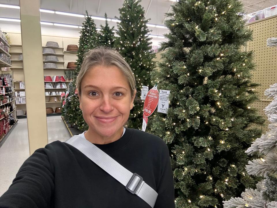 Author Terri Peters smiling in front of Christmas trees in a Hoby Lobby