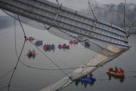 <p>Rescuers on boats search in the Machchu river next to a cable suspension bridge that collapsed in Morbi town of western state Gujarat, India, Monday, Oct. 31, 2022. The century-old cable suspension bridge collapsed into the river Sunday evening, sending hundreds plunging in the water, officials said. (AP Photo/Ajit Solanki)</p> 