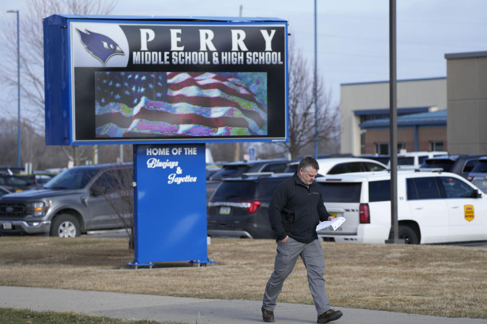 A law enforcement official walks past the school sign following a shooting at Perry High School, Thursday, Jan. 4, 2024, in Perry, Iowa. Multiple people were shot inside the school early Thursday as students prepared to start their first day of classes after their annual winter break, authorities said. (AP Photo/Charlie Neibergall)