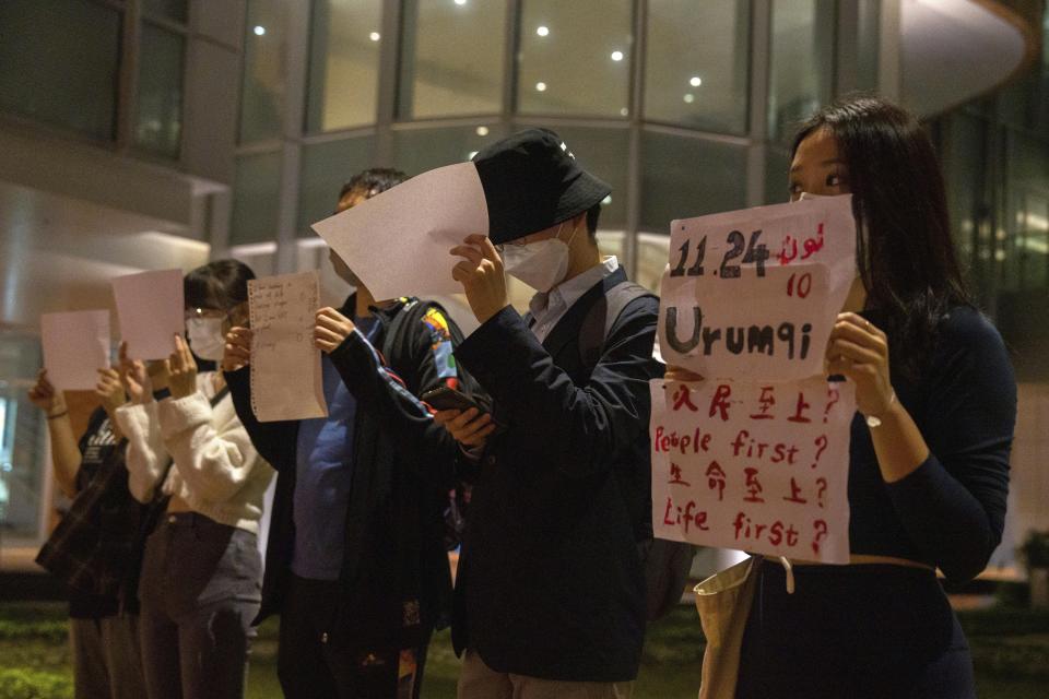 Protesters hold up white paper some with writings commemorating the Nov 24 deadly Urumqi fire during a gathering at the University of Hong Kong in Hong Kong, Tuesday, Nov. 29, 2022. On Tuesday, about a dozen people gathered at the University of Hong Kong, chanting against virus restrictions and holding up sheets of paper with critical slogans. Most were from the mainland, which has a separate legal system from the Chinese territory of Hong Kong, and some spectators joined in their chants. (AP Photo/Bertha Wang)