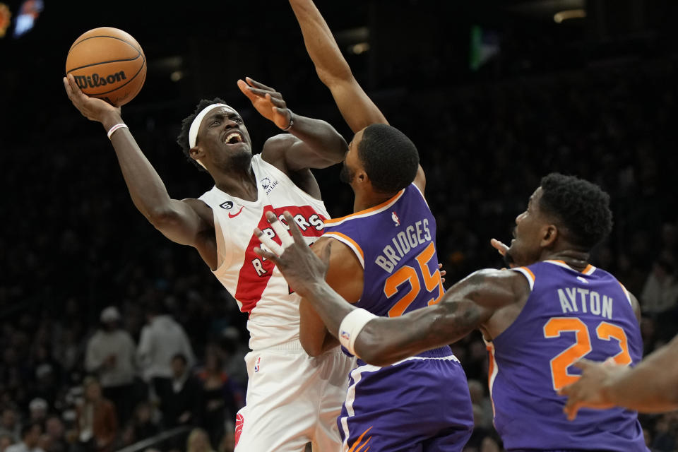 Toronto Raptors forward Pascal Siakam, left, shoots over Phoenix Suns forward Mikal Bridges (25) and center Deandre Ayton during the first half of an NBA basketball game, Monday, Jan. 30, 2023, in Phoenix. (AP Photo/Rick Scuteri)