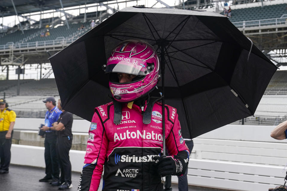 Helio Castroneves, of Brazil, walk out of the pit area as rain halted qualifications for the Indianapolis 500 auto race at Indianapolis Motor Speedway in Indianapolis, Saturday, May 21, 2022. (AP Photo/Michael Conroy)