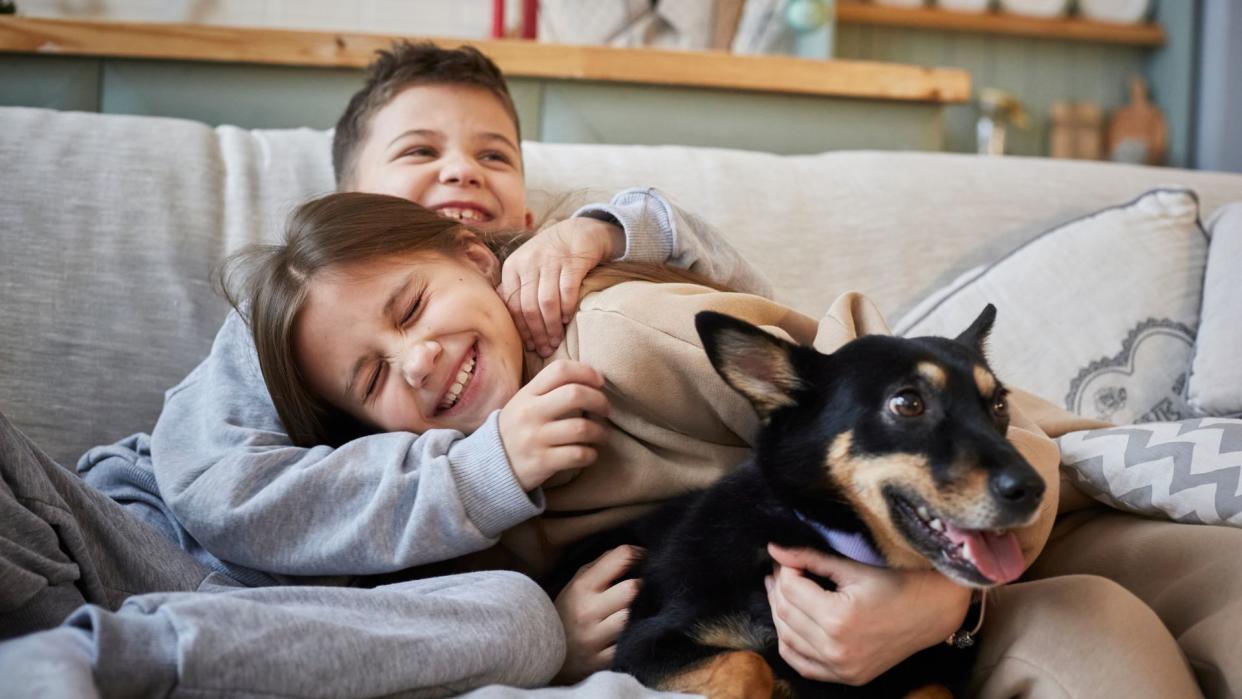 Two kids cuddling a dog