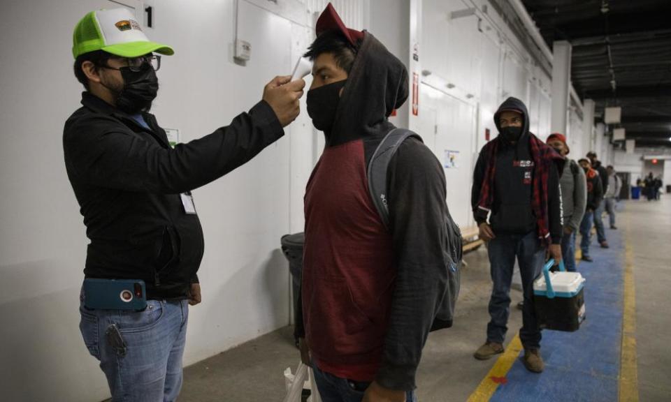 Migrant farm workers have their temperature checked before boarding the bus to their shift, 28 April 2020, in King City, California.