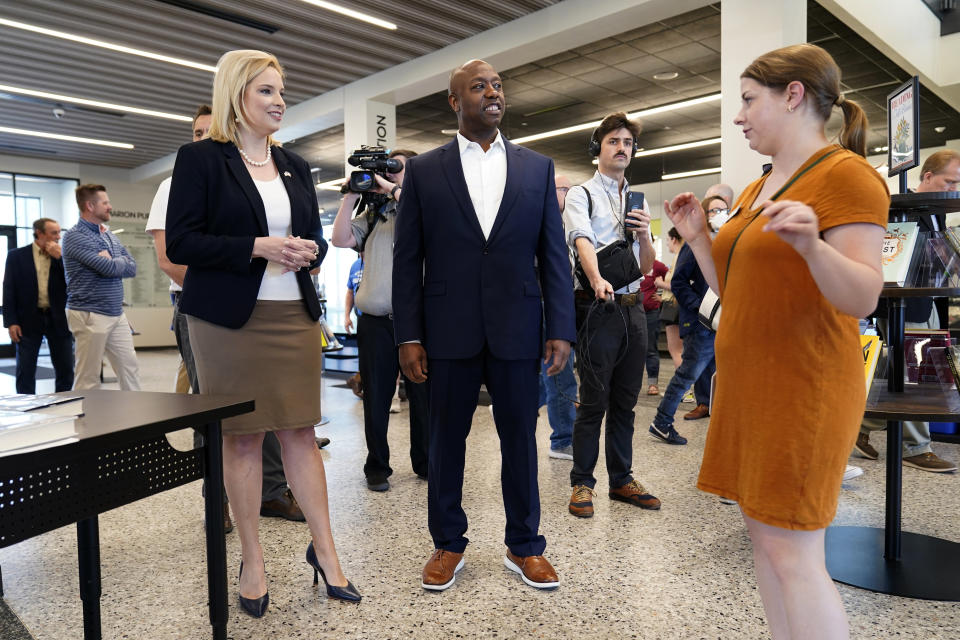 Sen. Tim Scott, R-S.C., center, tours the Marion Public Library with Rep. Ashley Hinson, R-Iowa, left, Wednesday, April 12, 2023, in Marion, Iowa. Scott on Wednesday launched an exploratory committee for a 2024 GOP presidential bid, a step that comes just shy of making his campaign official. (AP Photo/Charlie Neibergall)