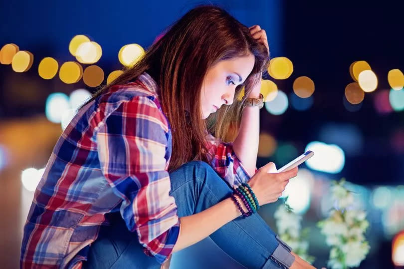 Depressed, young girl is texting on the bridge