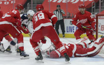 Detroit Red Wings goaltender Jonathan Bernier, right, lays out to stop a shot by Columbus Blue Jackets center Max Domi (16) as Red Wings defenseman Danny DeKeyser (65) and right-wing Anthony Mantha (39) help defend during the first period of an NHL hockey game Tuesday, Jan. 19, 2021, in Detroit. (AP Photo/Duane Burleson)