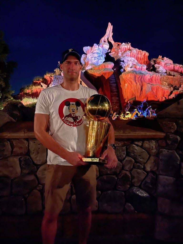 Milwaukee Bucks center Brook Lopez holds the Larry O'Brien NBA championship trophy in front of Splash Mountain at Disney World in Orlando, Florida.