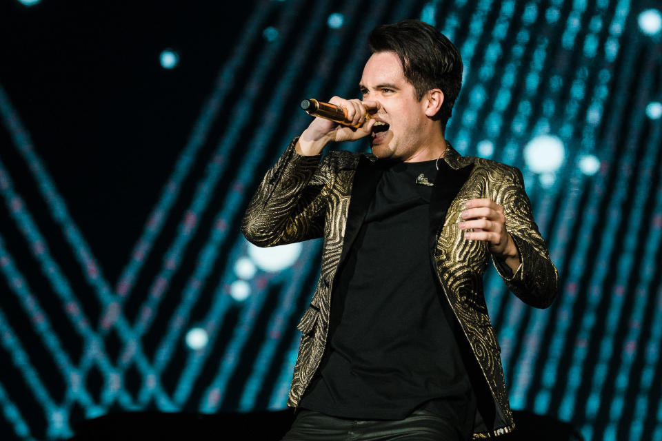 Brendon singing passionately onstage while wearing a t-shirt and blazer
