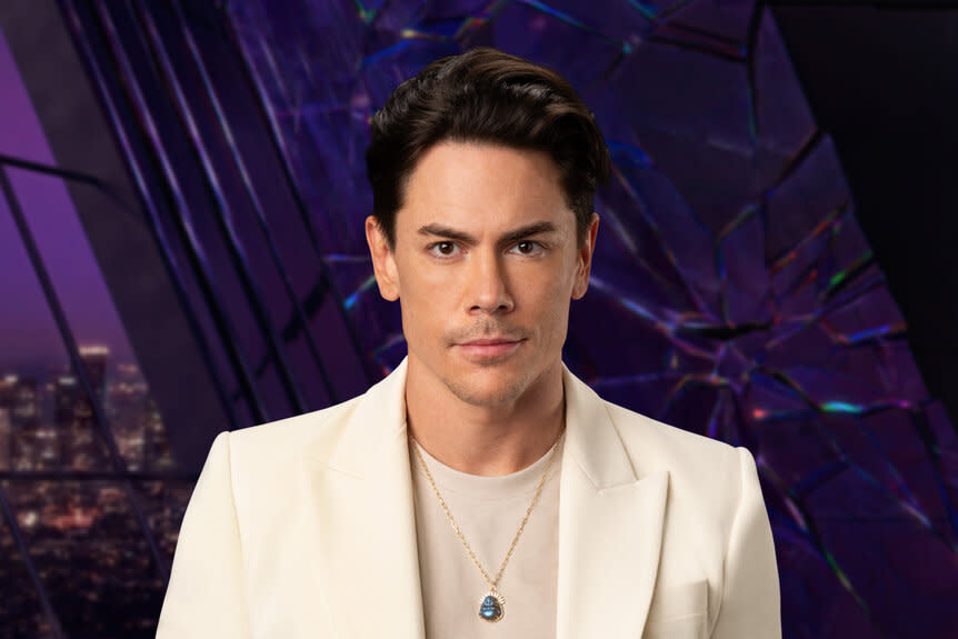 Tom Sandoval wearing a white suit while in a purple room overlooking LA.