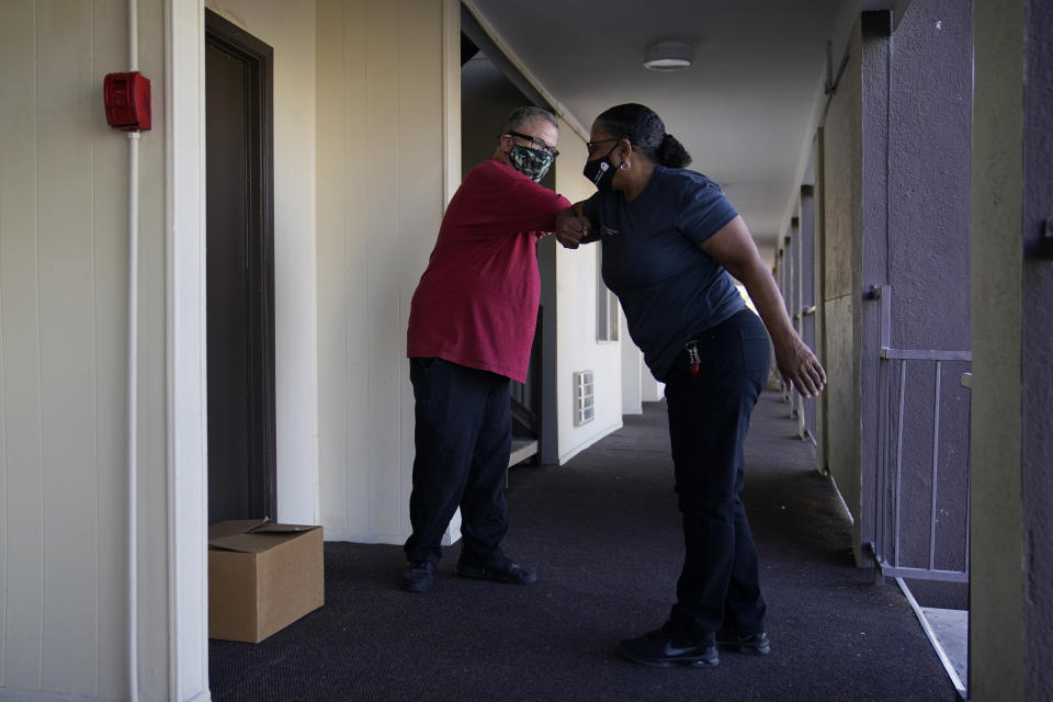 Larry Holt, left, thanks Diana Everett after she delivered a box of food to his apartment, Thursday, Nov. 19, 2020, in Las Vegas. Holt lost his casino job during the coronavirus pandemic and receives assistance from a food bank. (AP Photo/John Locher)