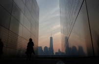 A woman looks at names of victims on the wall of the 9/11 Empty Sky memorial at sunrise across from New York's Lower Manhattan and One World Trade Center in Liberty State Park in Jersey City, New Jersey, September 11, 2013. Americans will commemorate the 12th anniversary of the September 11 attacks with solemn ceremonies and pledges to not forget the nearly 3,000 killed when hijacked jetliners crashed into the World Trade Center, the Pentagon, and a Pennsylvania field. (REUTERS/Gary Hershorn)