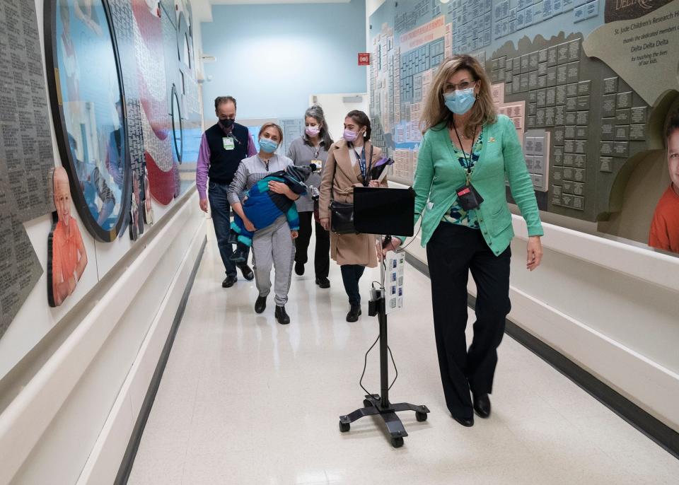 A hospital staff member wheels an electronic translation device as a Ukrainian mother carries her sick child into St. Jude Children's Research Hospital in Memphis.