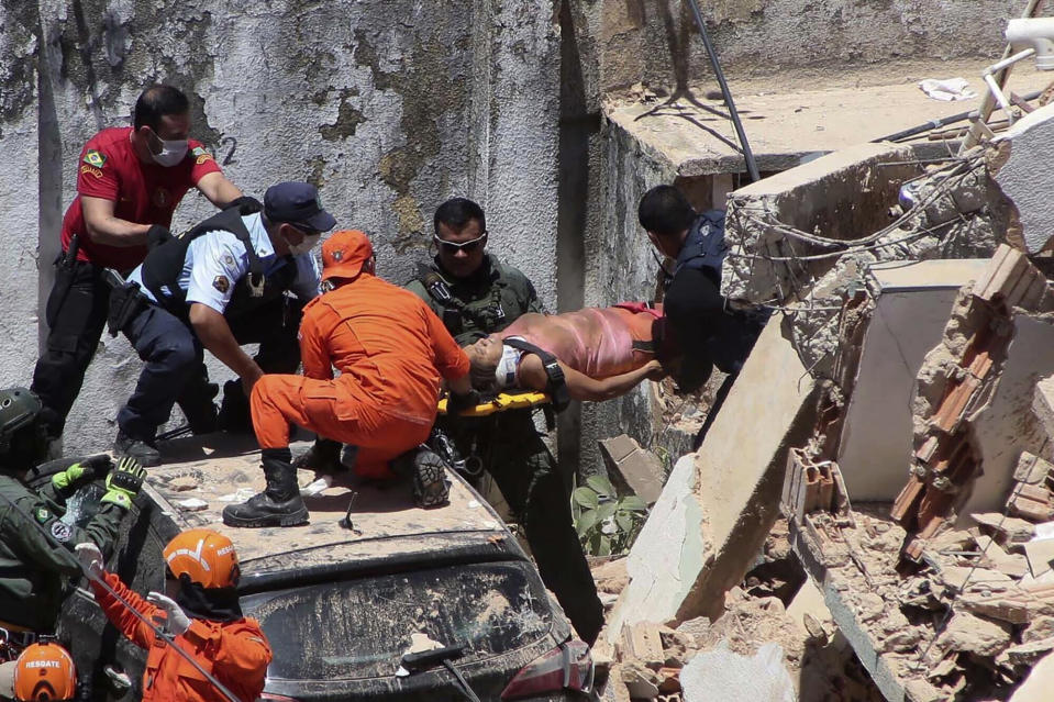 Firefighters rescue a woman from a building that collapsed in Fortaleza, Ceara state, Brazil, Tuesday, Oct. 15, 2019. A seven-story building collapsed Tuesday in the northeastern city of Fortaleza, killing at least three people City authorities informed several others are under the debris, and some of them are communicating with relatives and rescue teams by telephone. (Kleber Goncalves/Futura Press via AP)