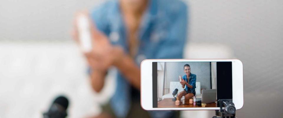 close up of smartphone on tripod, filming woman displaying product while sitting on a couch