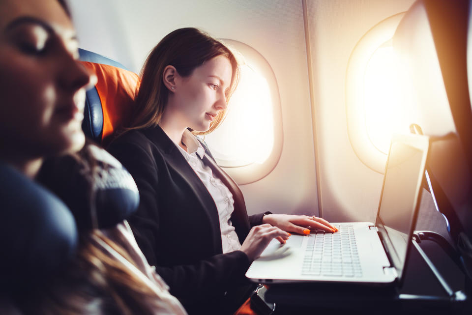 A woman using a laptop on a plane.