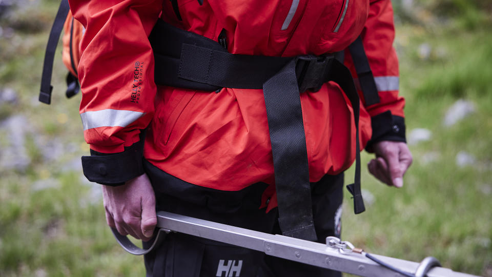 A close-up of a mountain rescue volunteer, wearing a red Helly Hansen jacket and showing the cinches around the wrists.