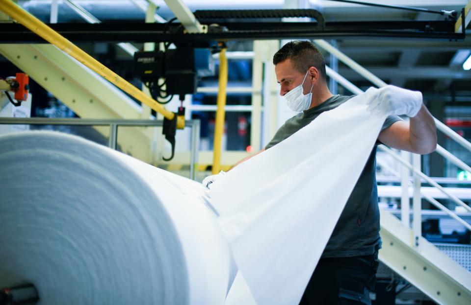 A worker checks the quality of non-woven fabric, produced for protective masks at the Innovatec production facility in Troisdorf, western Germany on June 25, 2020. - The North Rhine-Westphalian company intends to produce an additional 1500 tons of nonwoven matrial per year in the future with the two newly installed subsidized meltblown lines. The additional volume will enable the production of more than 1.5 billion protective masks. (Photo by Ina FASSBENDER / AFP) (Photo by INA FASSBENDER/AFP via Getty Images)