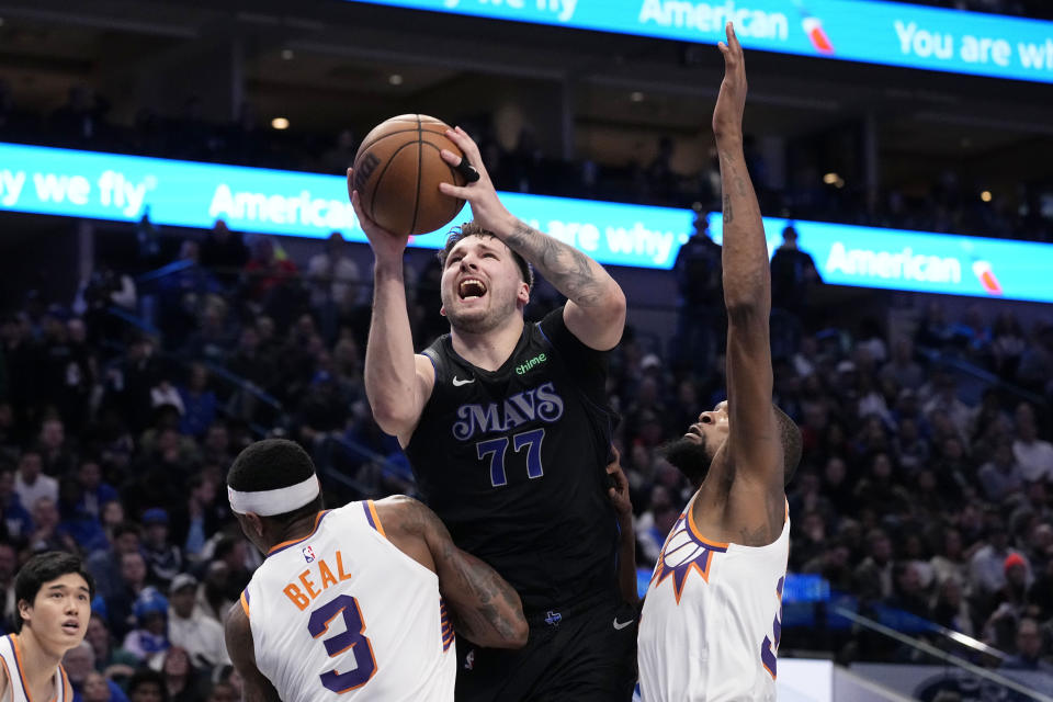 Dallas Mavericks guard Luka Doncic (77) takes a shot between Phoenix Suns' Bradley Beal (3) and Kevin Durant, right, in the first half of an NBA basketball game in Dallas, Wednesday, Jan. 24, 2024. (AP Photo/Tony Gutierrez)