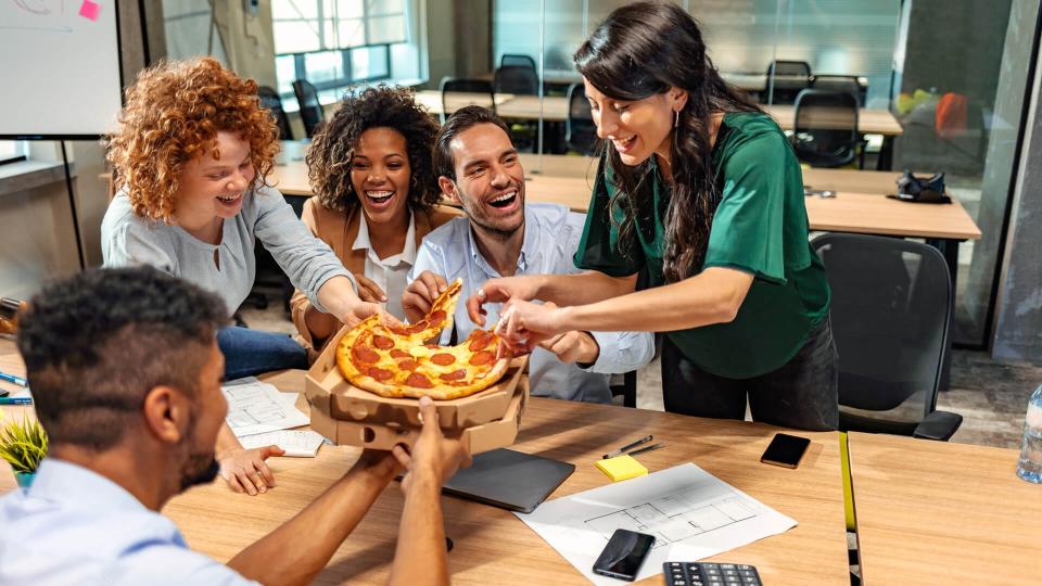 Office staff eating pizza in the business office.