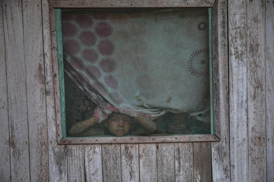 Boys watch as a government team disinfect the body of their relative Manuela Chavez, who died from symptoms related to the new coronavirus at the age of at the age of 88, after removing the body from inside her home in the Shipibo Indigenous community of Pucallpa, in Peru’s Ucayali region, Monday, Aug. 31, 2020. In the Ucayali region, government rapid response teams deployed to a handful of indigenous communities have found infection rates as high as 80% through antibody testing. (AP Photo/Rodrigo Abd)