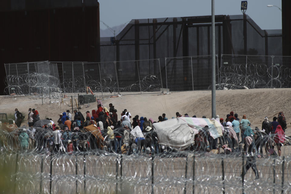 Migrants wait for U.S. authorities, between a barbed-wire barrier and the border fence at the US-Mexico border, as seen from Ciudad Juarez, Mexico, Wednesday, May 10, 2023. The U.S on May 11 will begin denying asylum to migrants who show up at the U.S.-Mexico border without first applying online or seeking protection in a country they passed through, according to a new rule released May 10. (AP Photo/Christian Chavez)