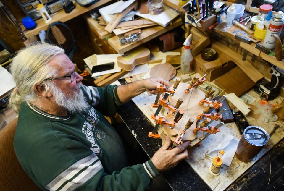 Musician and ukulele luthier Dave Birney glues and braces the backside of one of his handcrafted ukuleles together at his shop in Mason.